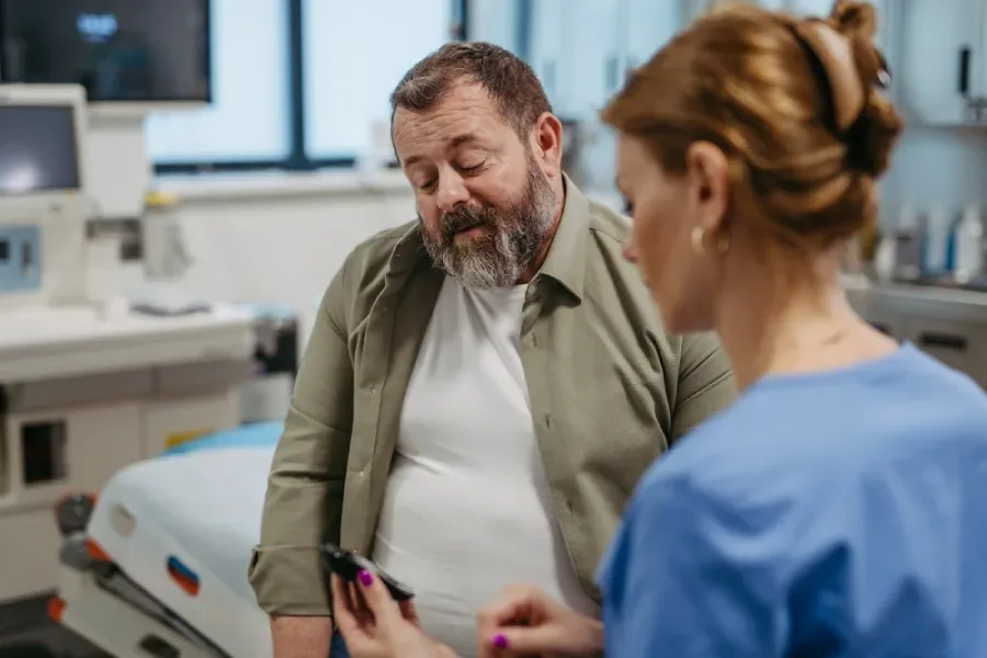 A healthcare worker takes time to check a patient’s blood glucose levels in the hospital setting.