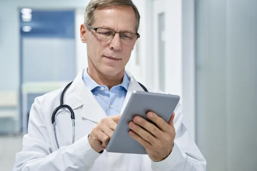 A physician oversees an automated process on a tablet.
