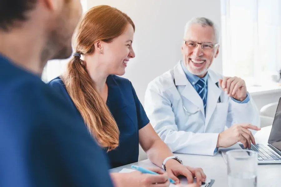 A patient’s care team smiles and laughs together at a meeting.