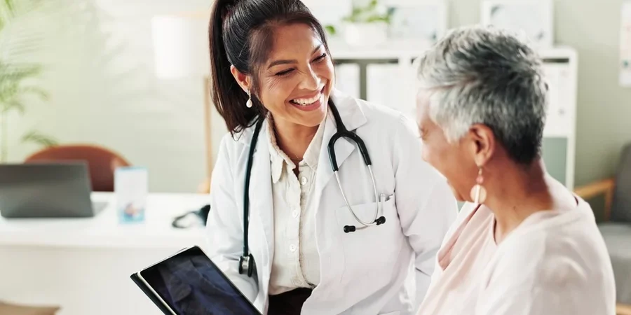 A doctor and patient connect while looking over information on a tablet.