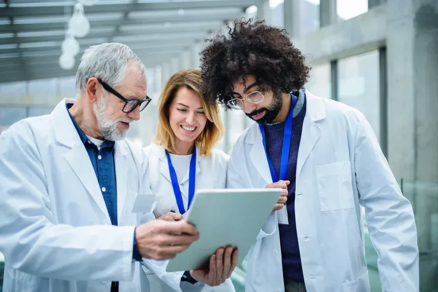 A group of doctors consult a tablet while attending a healthcare conference.