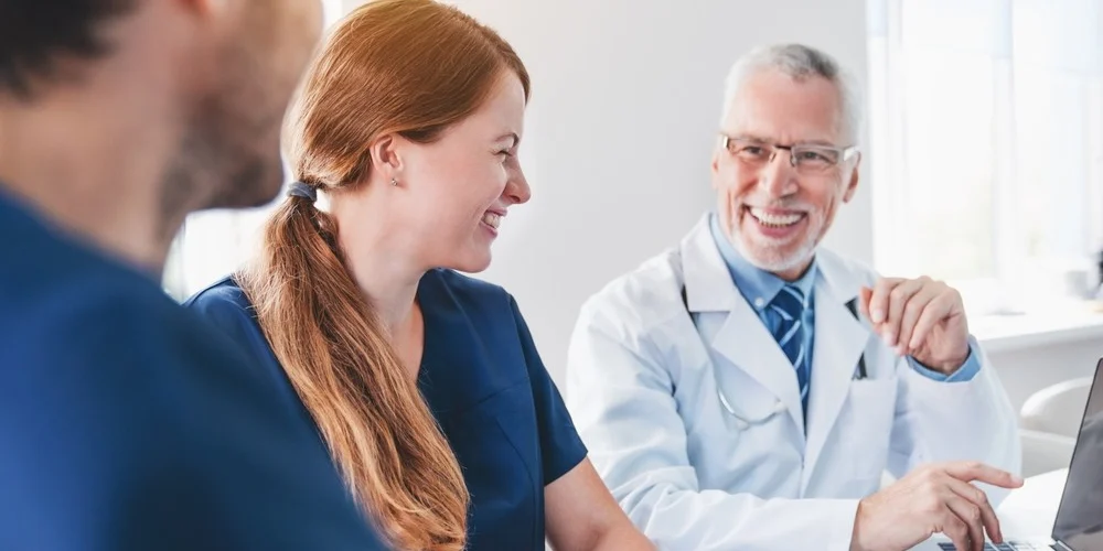 Happy hospital patient flow team chats during a meeting.